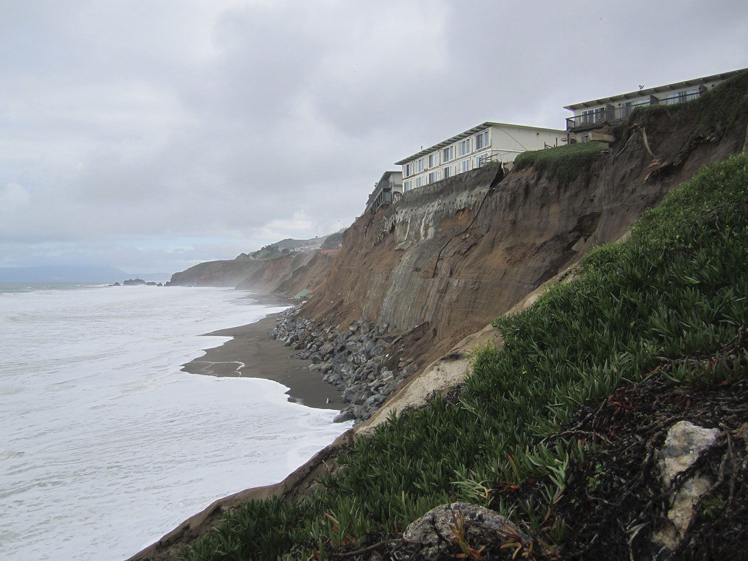 An eroding coastal cliff beneath apartment buildings in Pacifica, California.